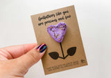 a hand holding a purple heart shaped cookie